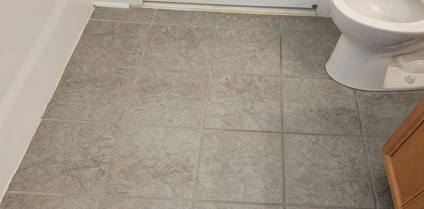 Before: a gray tile bathroom floor with grout the same dark gray as the tile.