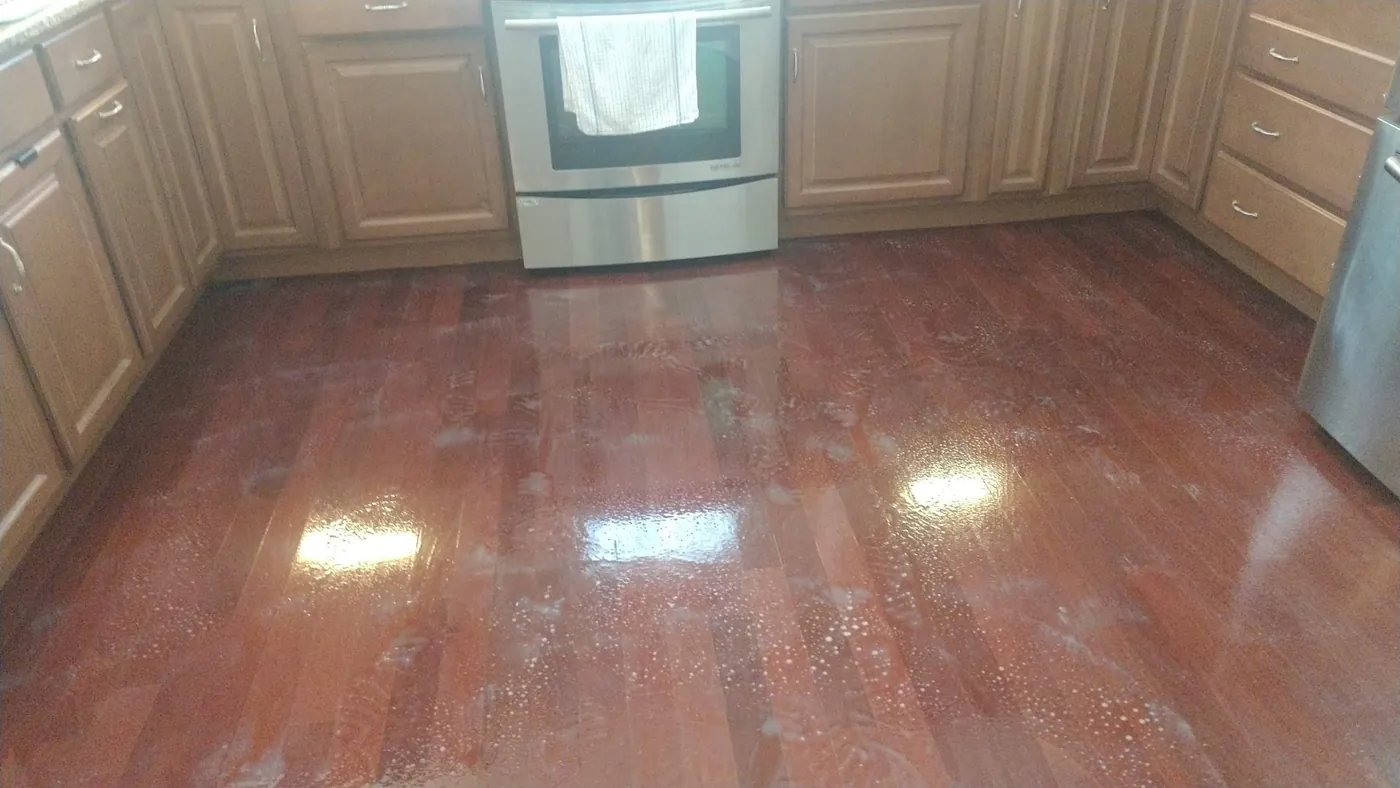 A cherry hardwood kitchen floor shining under the lights.