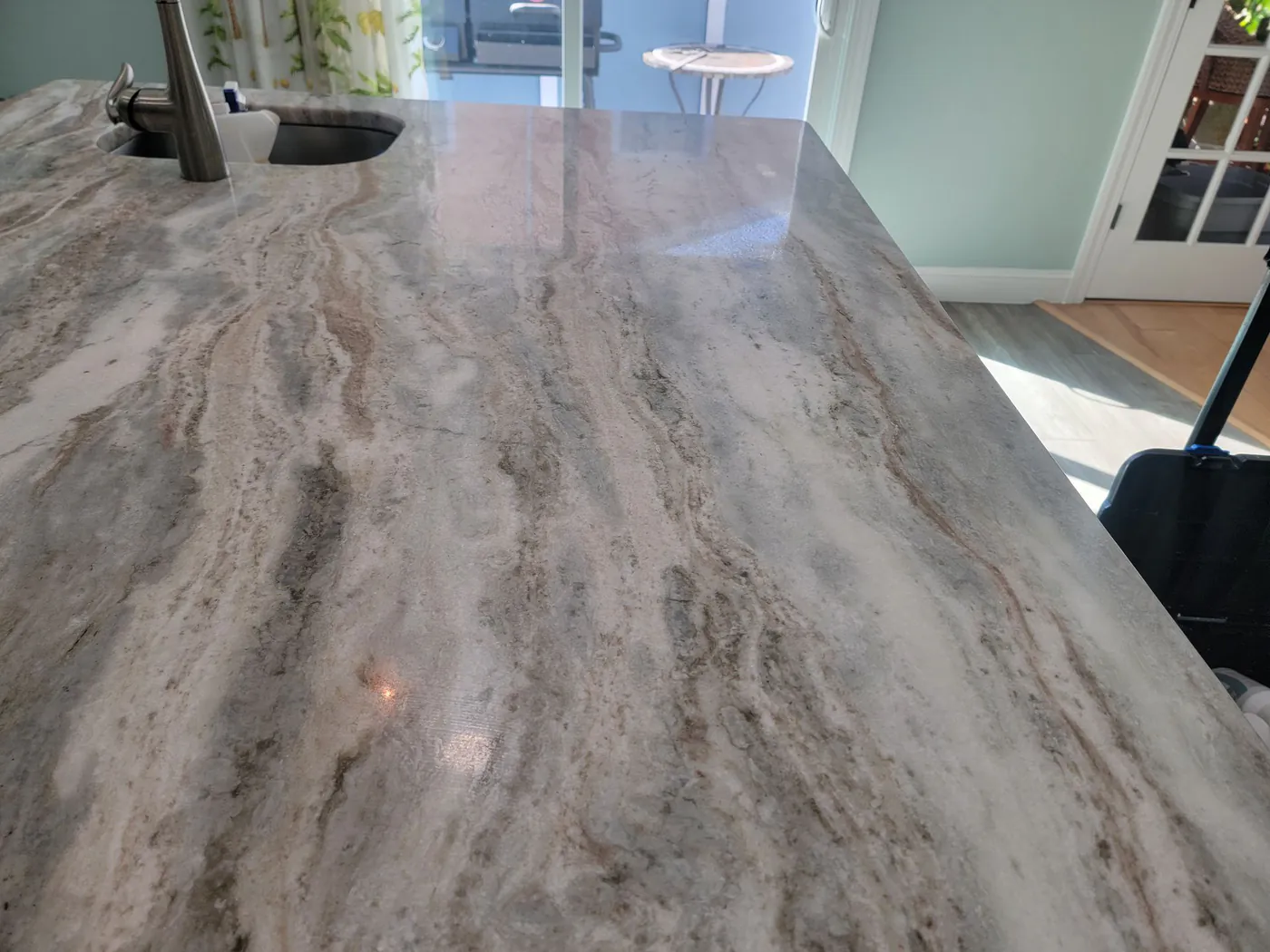 A kitchen island with flowing gray, brown and white stone, freshly polished.