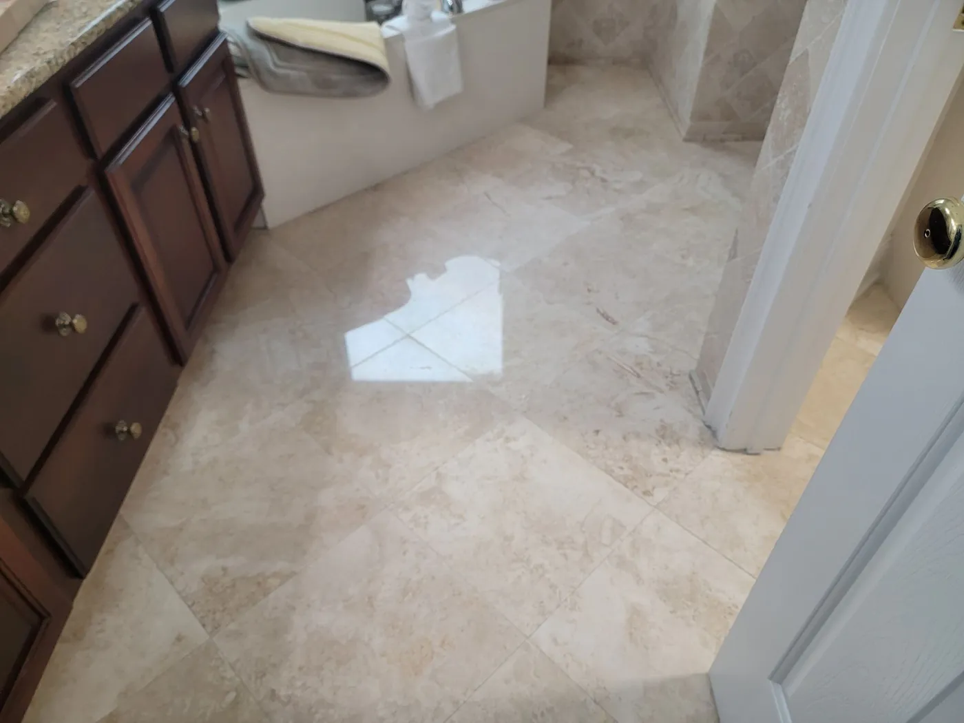 A beige marble bathroom floor beside dark wood cabinets.