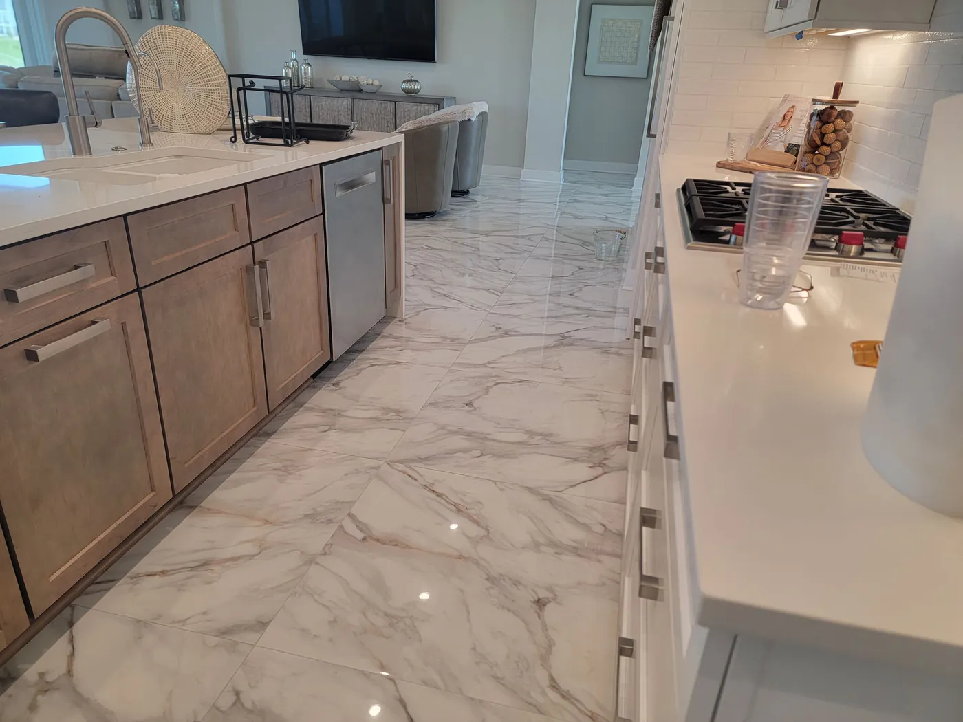 A polished marble kitchen floor with light wood cabinets.