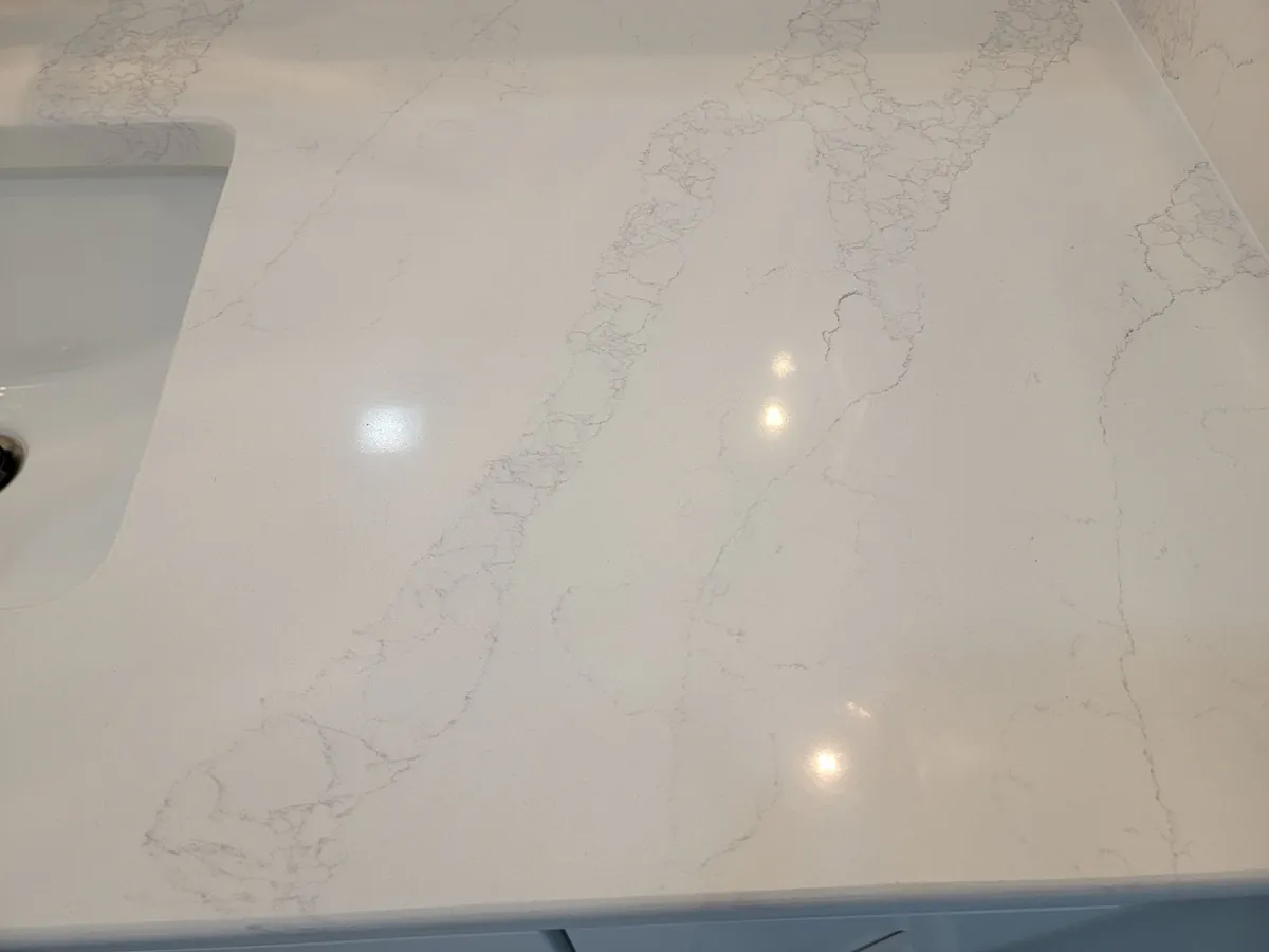 A white countertop with gray veining near a sink basin.