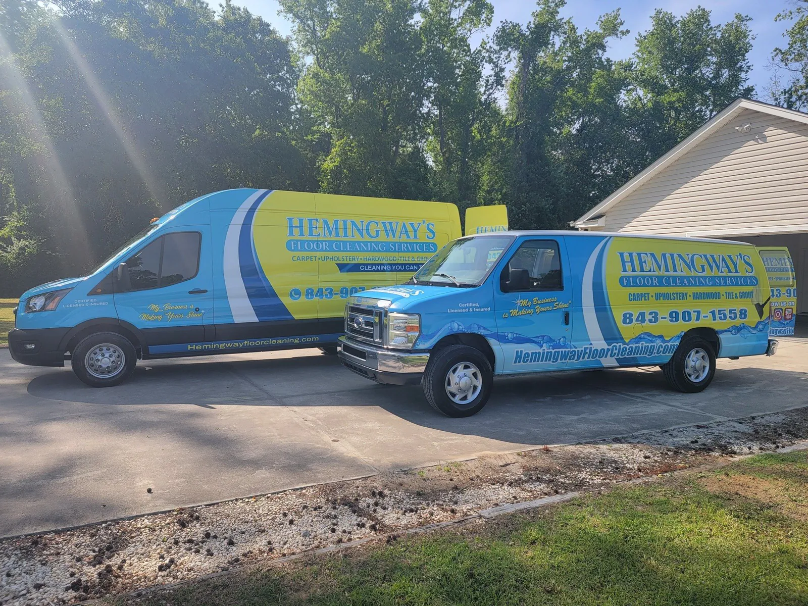 Two Hemingway's Floor Cleaning vans, one blue and one yellow, parked in a driveway.